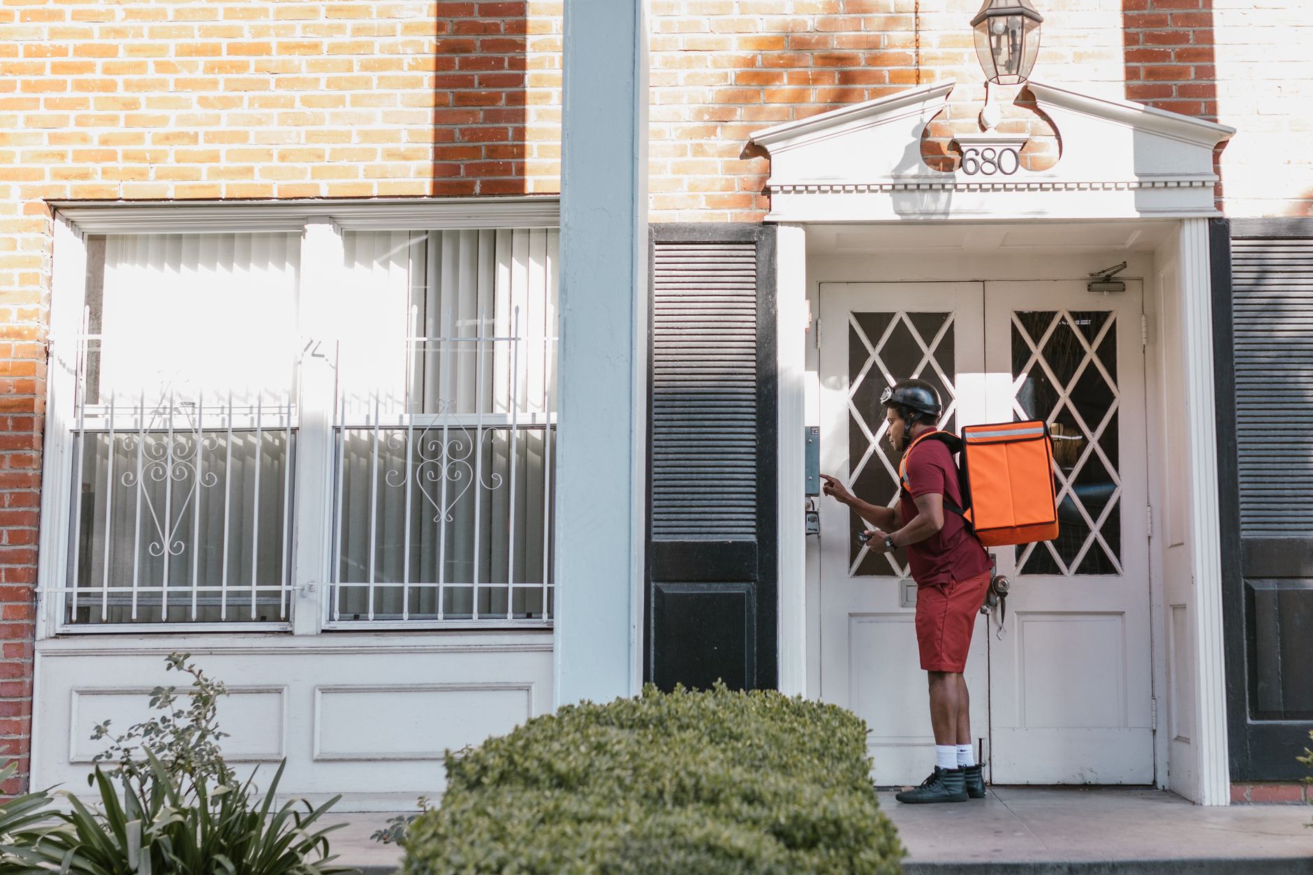 Delivery person pressing a residential doorbell.