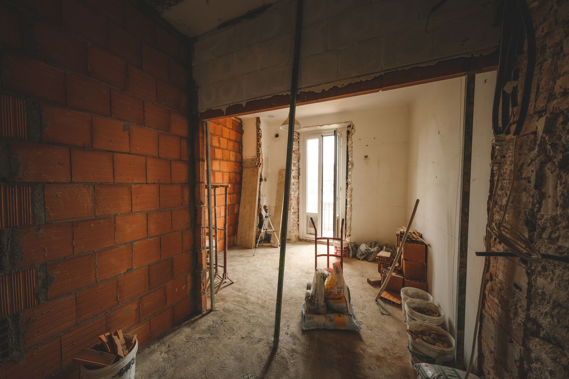 Room under renovation with exposed brick walls and materials on site